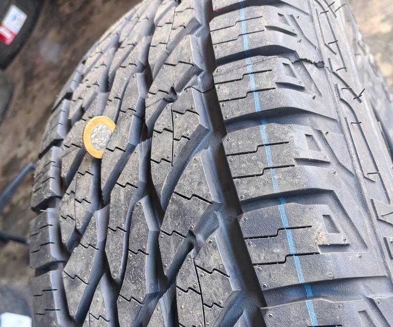 Coin placed in a tread groove of a new all-terrain tyre to gauge tread depth
